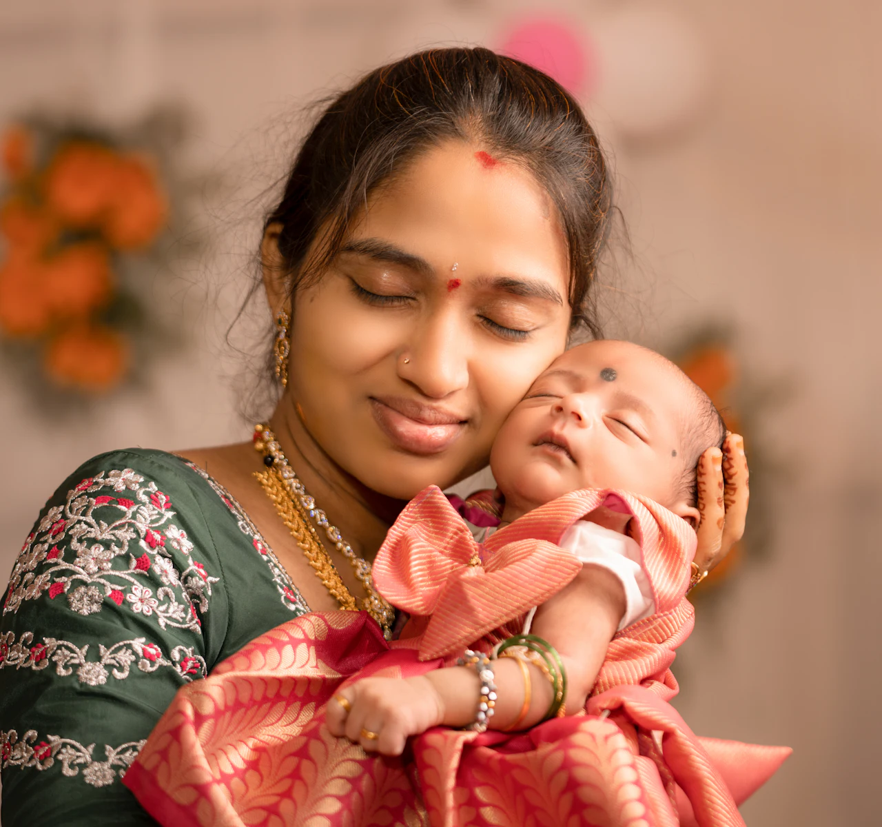 A smiling mother, eyes closed, holding her sleeping newborn to her cheek